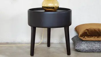 Runder Beistelltisch von Bielefelder Werkstätten in schwarzem Finish mit schlanken Beinen, dekoriert mit einer goldfarbenen Tischleuchte. Stilvolle Ergänzung für moderne Wohnräume, erhältlich bei himmlisch wohnen.